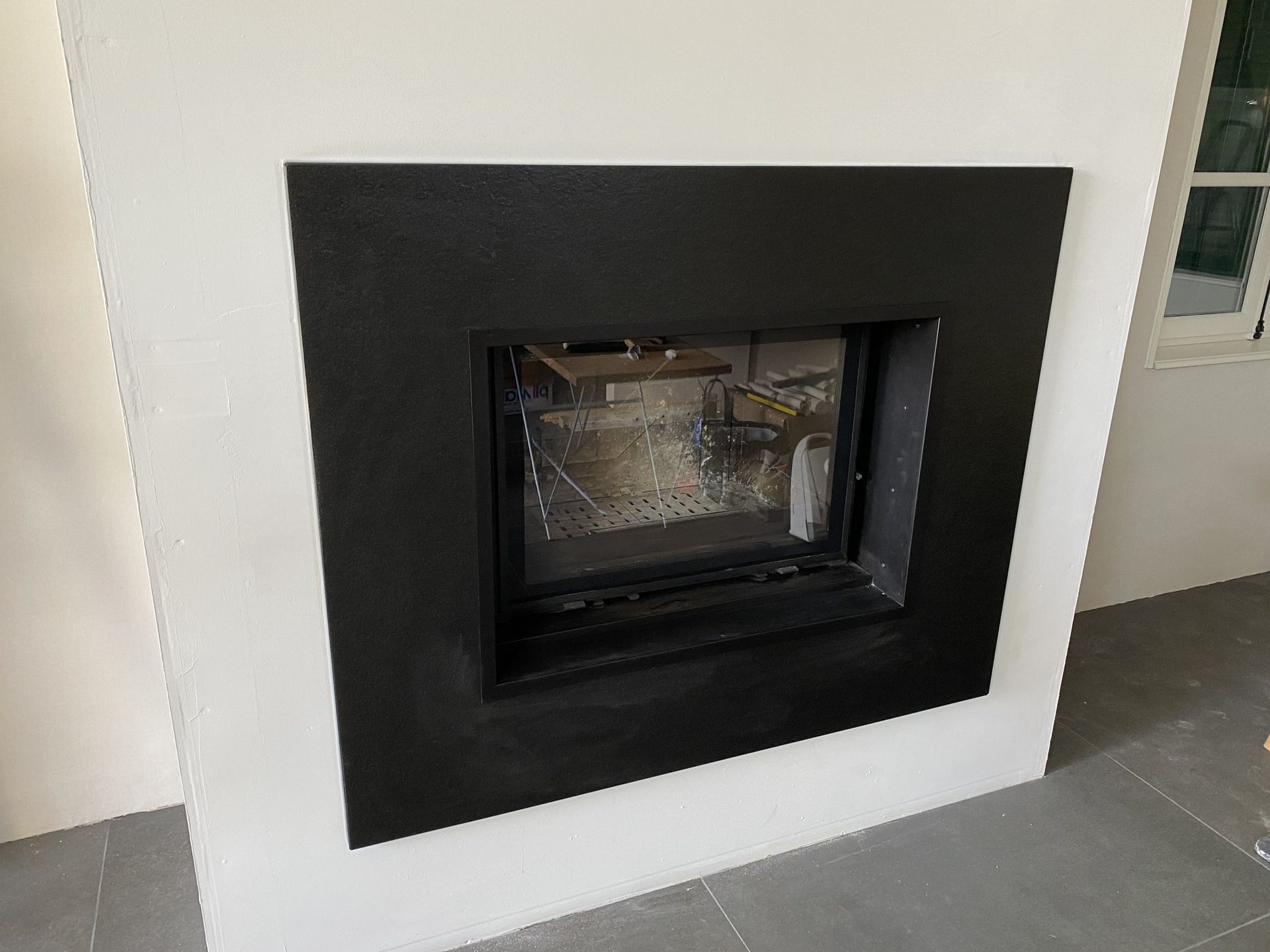 Cheminée noire encastrée dans un mur blanc.