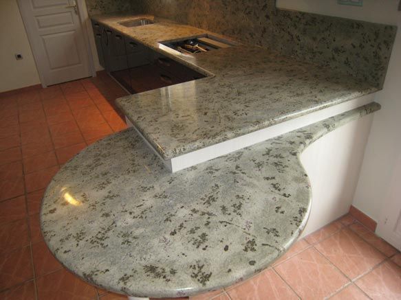 Cuisine avec comptoirs en granit ; une section arrondie fait saillie du comptoir principal.