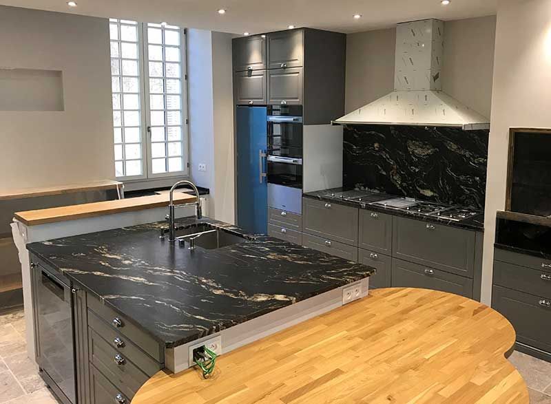 Cuisine moderne avec comptoirs foncés, armoires grises et îlot en bois.