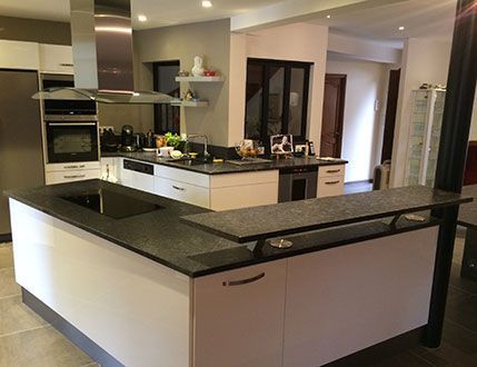 Cuisine moderne avec armoires blanches, comptoirs foncés et électroménagers en acier inoxydable.