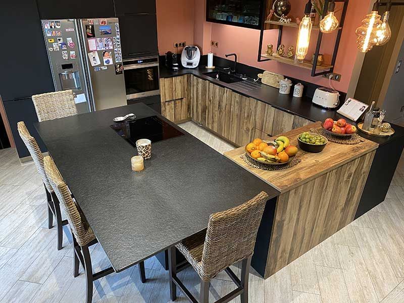 Cuisine moderne avec comptoirs foncés, armoires en bois et un grand îlot avec des places assises.