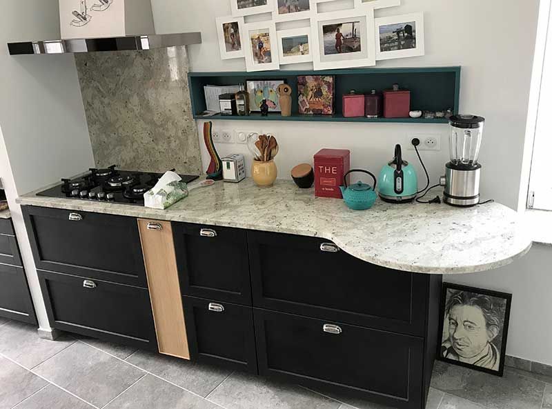 Cuisine avec placards noirs, comptoir en granit, électroménager et éléments décoratifs.