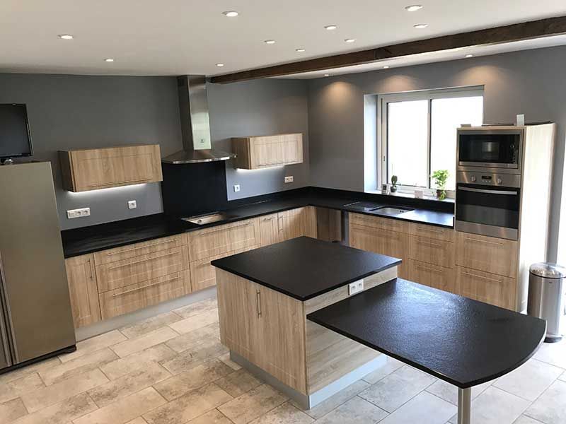 Cuisine moderne avec armoires en bois, comptoirs foncés et îlot avec coin repas.