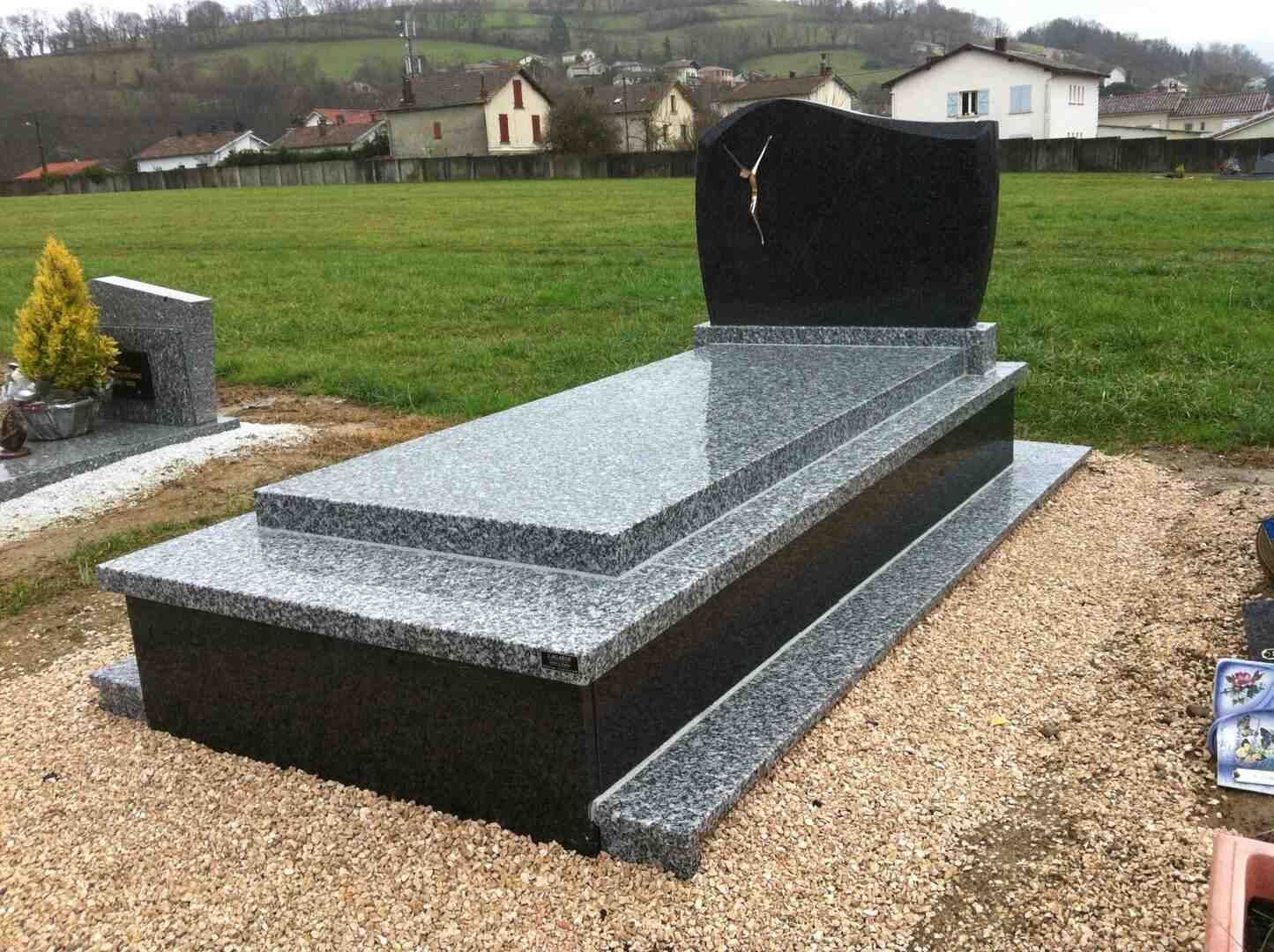 Une pierre tombale en granit poli dans un cimetière ; un dessus sombre avec une base en granit plus clair.