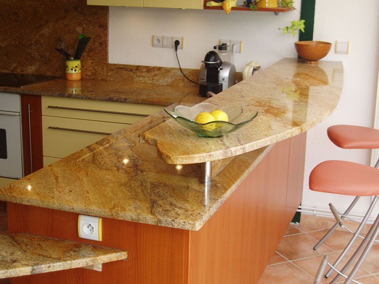 Cuisine avec comptoir-bar en granit et tabourets de bar orange.