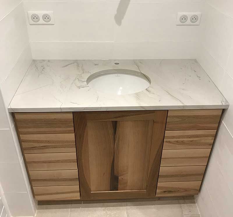 Meuble-lavabo de salle de bain avec comptoir en marbre blanc et armoires en bois.