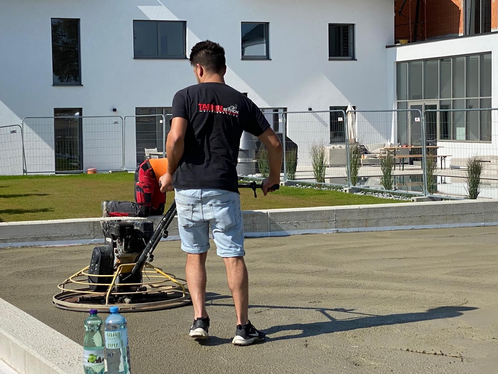 Ein Mann steht auf einer Baustelle neben einer Maschine.