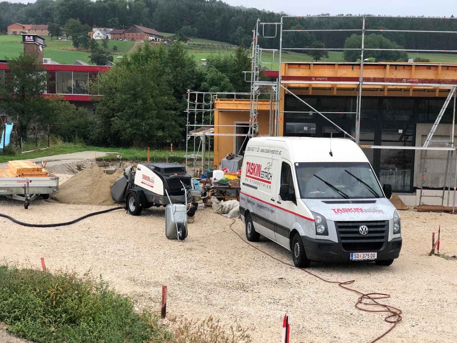 Ein weißer Lieferwagen parkt vor einem im Bau befindlichen Gebäude.