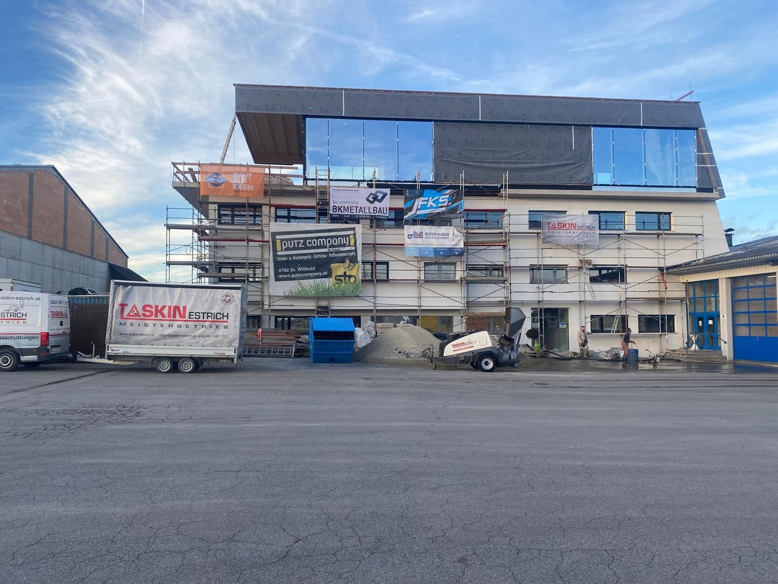 Ein großes Gebäude im Bau, vor dem ein Lastwagen geparkt ist.