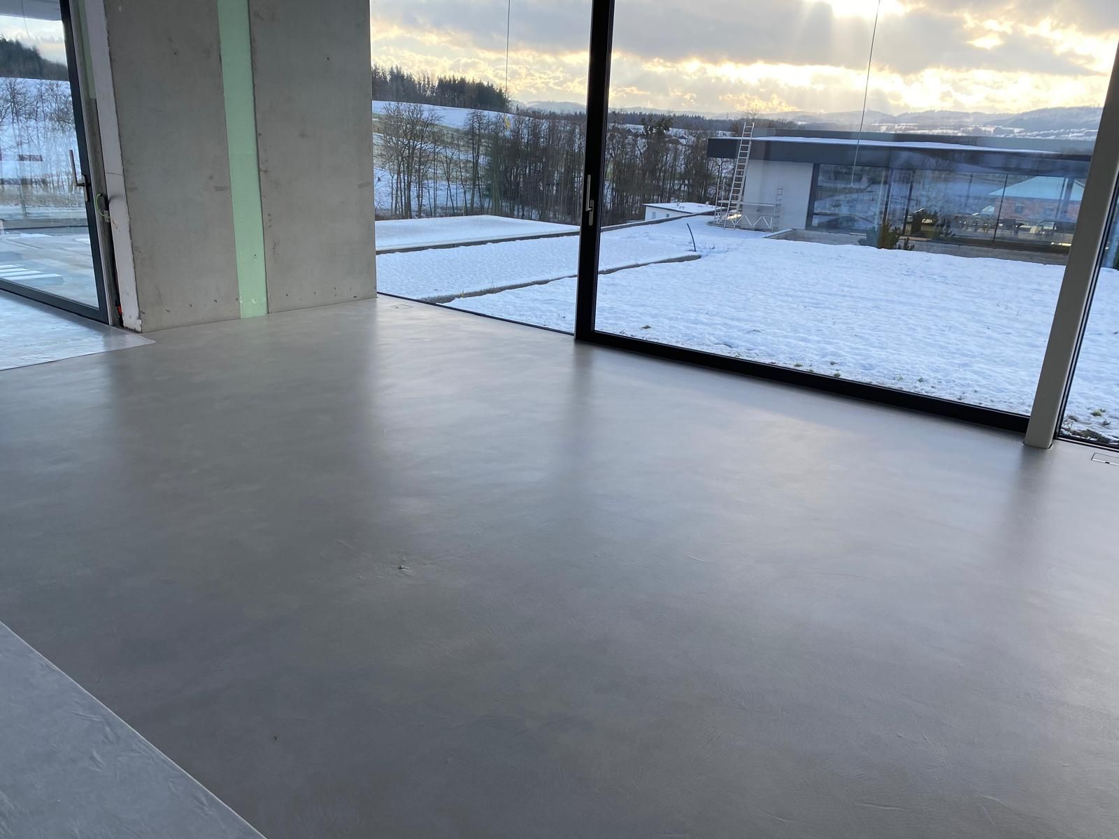 Ein Zimmer mit großem Fenster und Blick auf ein schneebedecktes Feld.