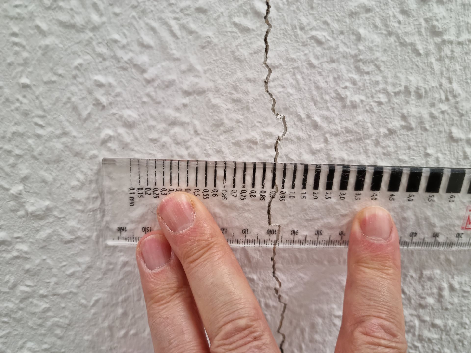 Backsteinmauer mit rissigem und abblätterndem Putz.