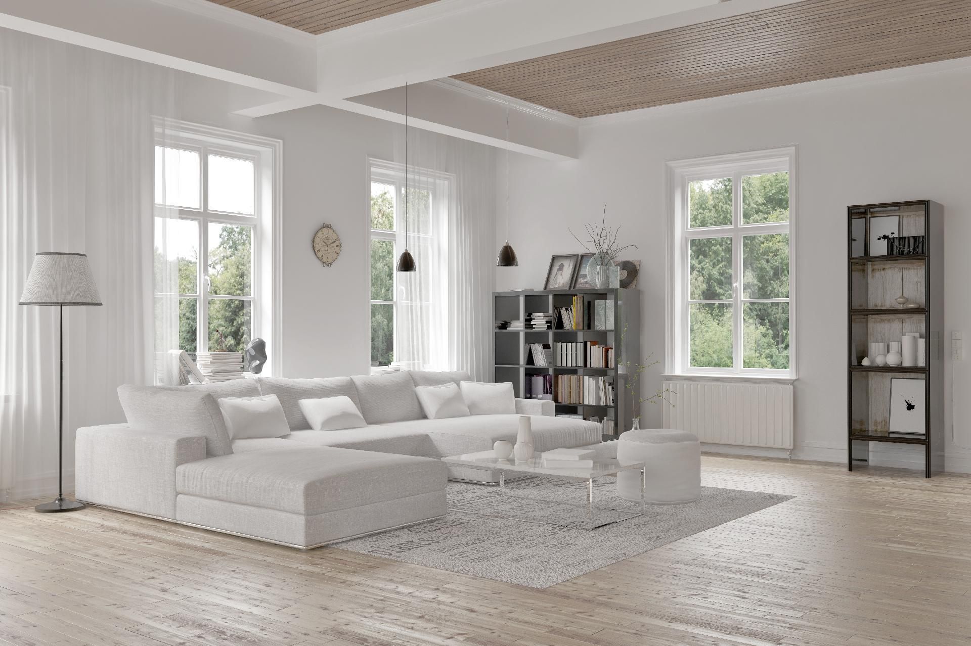 Helles Wohnzimmer mit weißem Ecksofa, großen Fenstern, Bücherregal und hellem Holzboden.