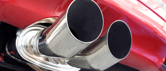 Um close de um cano de escapamento de aço inoxidável em um carro vermelho.