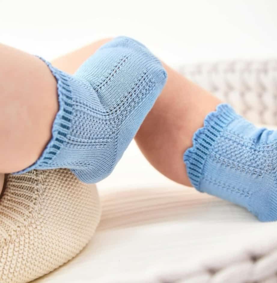Un bebé lleva un par de calcetines azules.