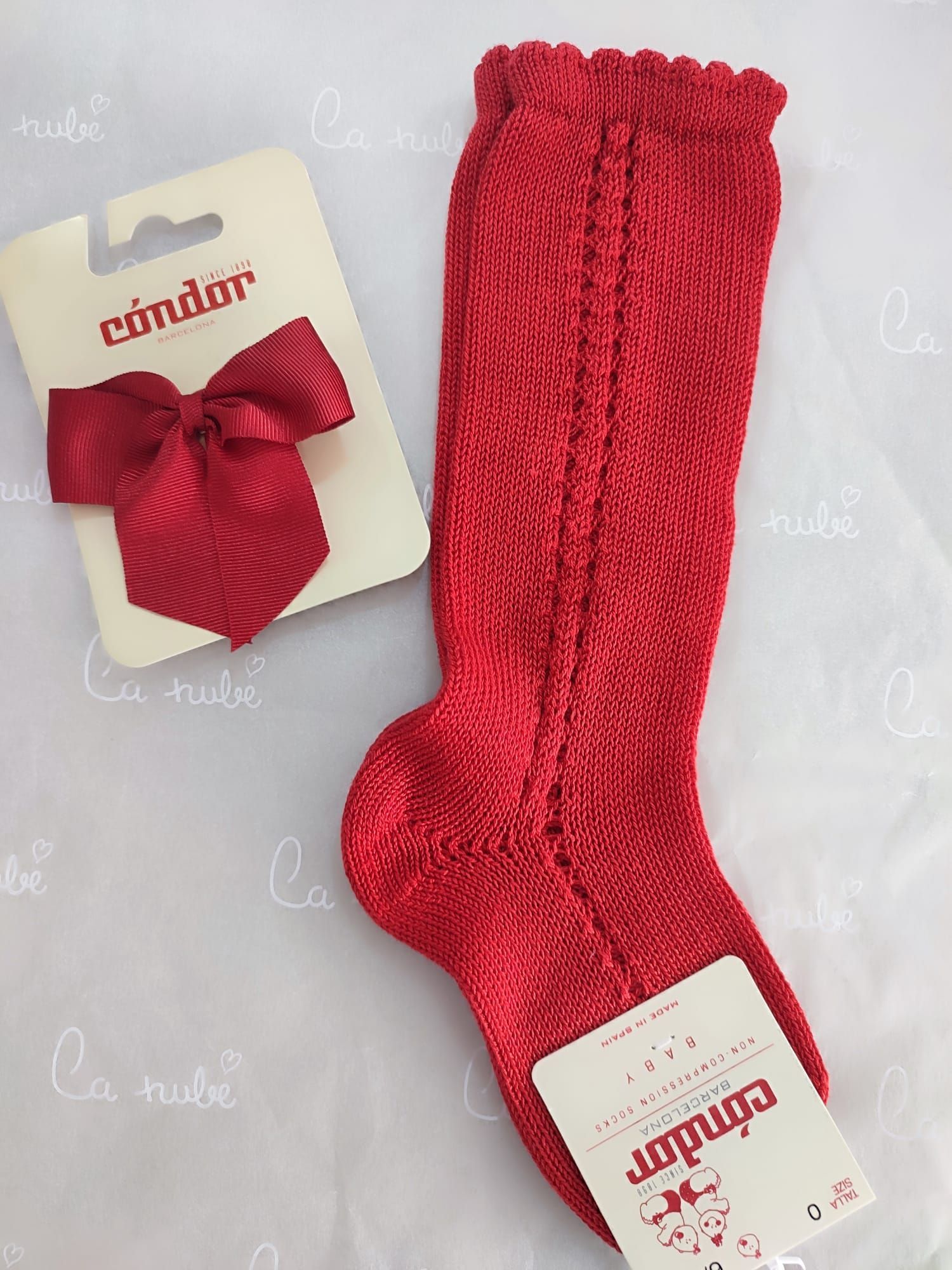 Un par de calcetines rojos hasta la rodilla con un lazo rojo.