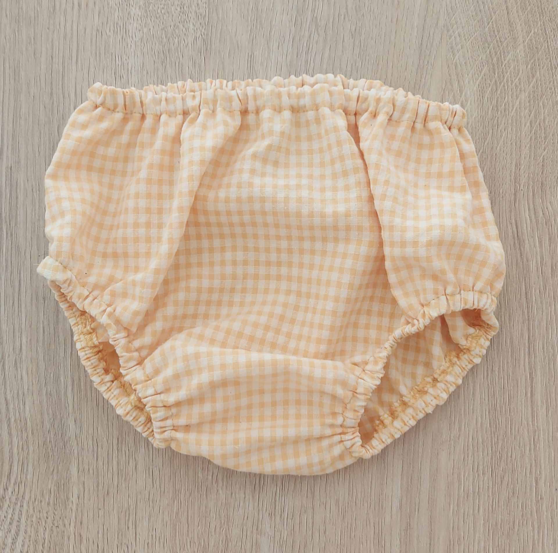 Un par de ropa interior de cuadros vichy está sobre una mesa de madera.