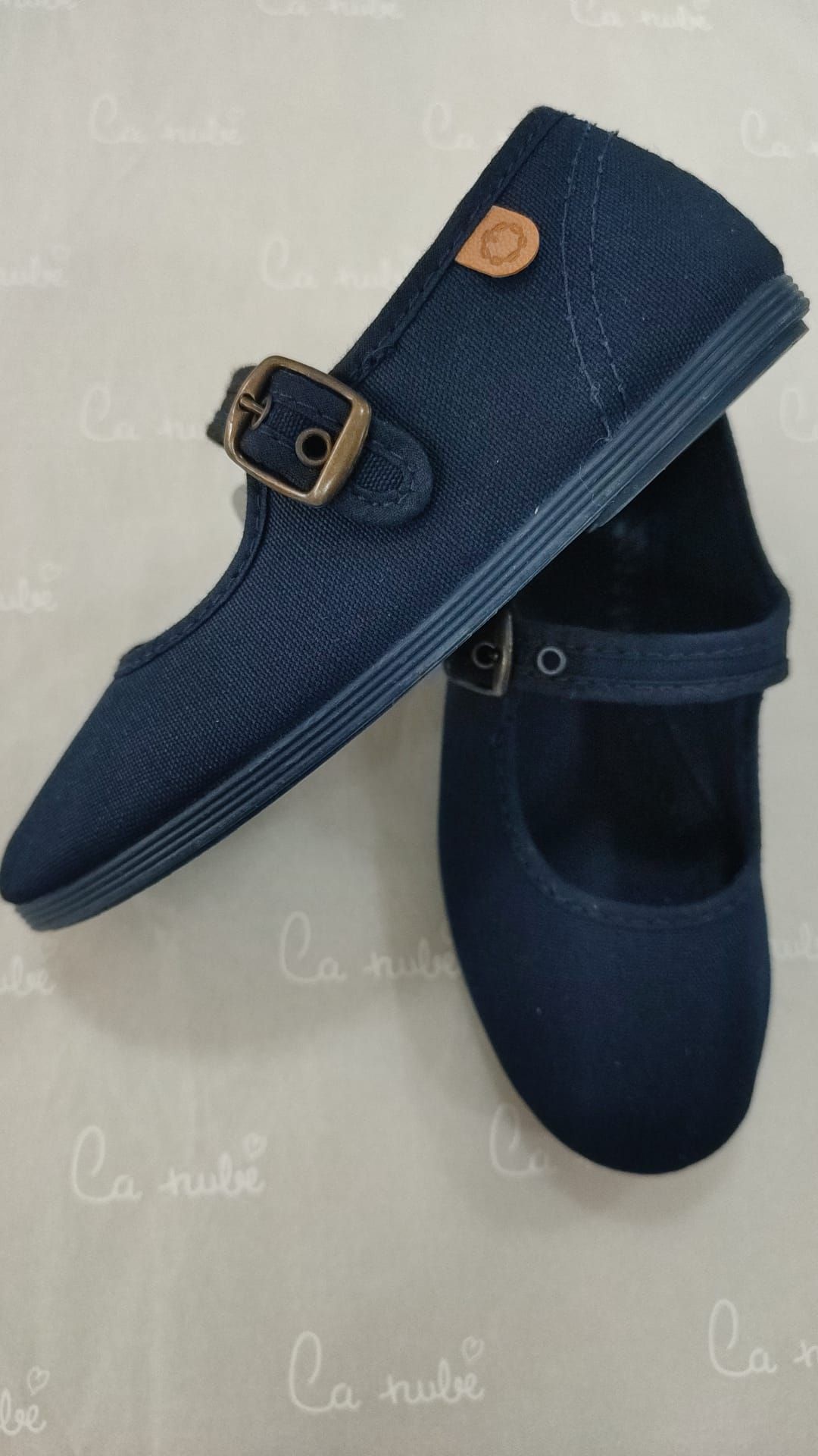 Un par de zapatos azules con una hebilla sobre una mesa.