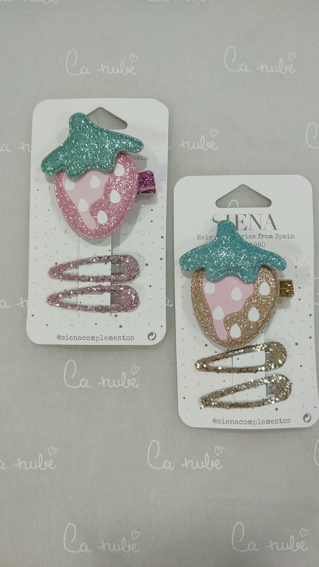 Sobre una mesa hay dos pinzas para el pelo con fresas.