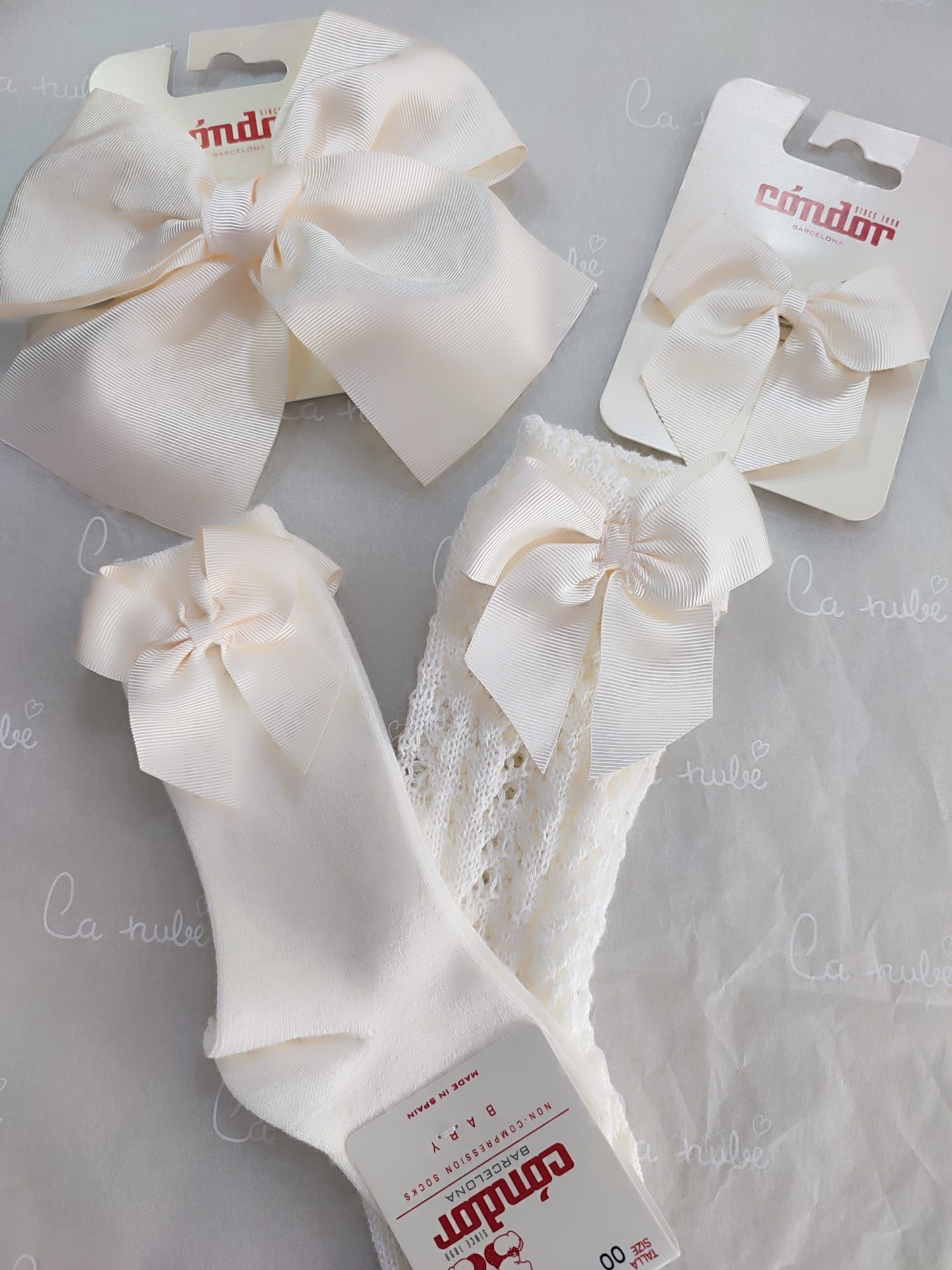 Un par de calcetines blancos con lazos y un par de pinzas para el pelo blancas.