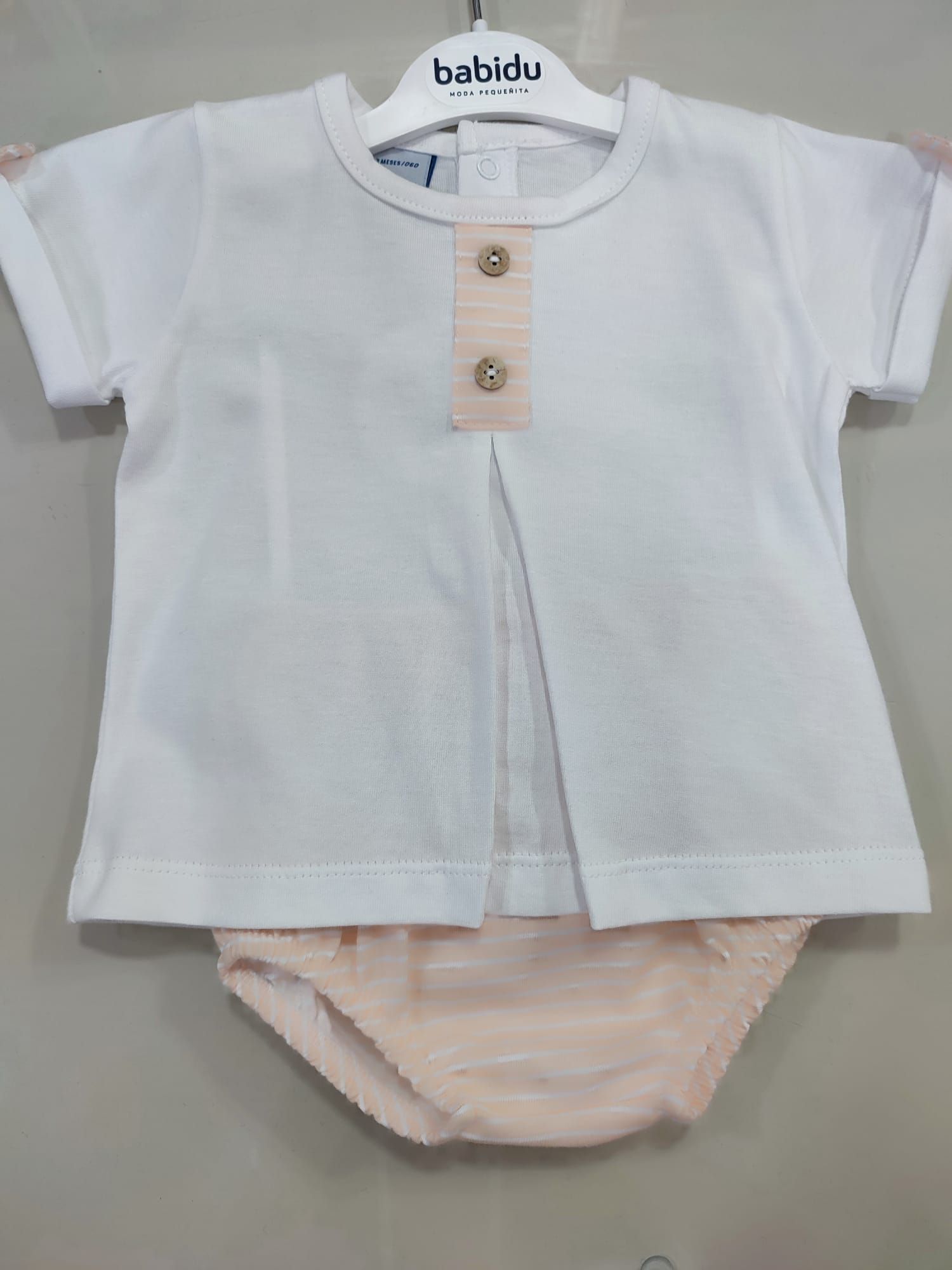 Un bebé lleva una camisa blanca y ropa interior rosa.