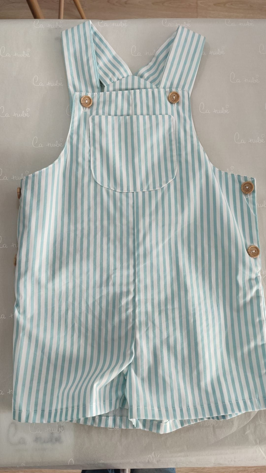 Sobre una mesa hay un mono de rayas de un bebé.