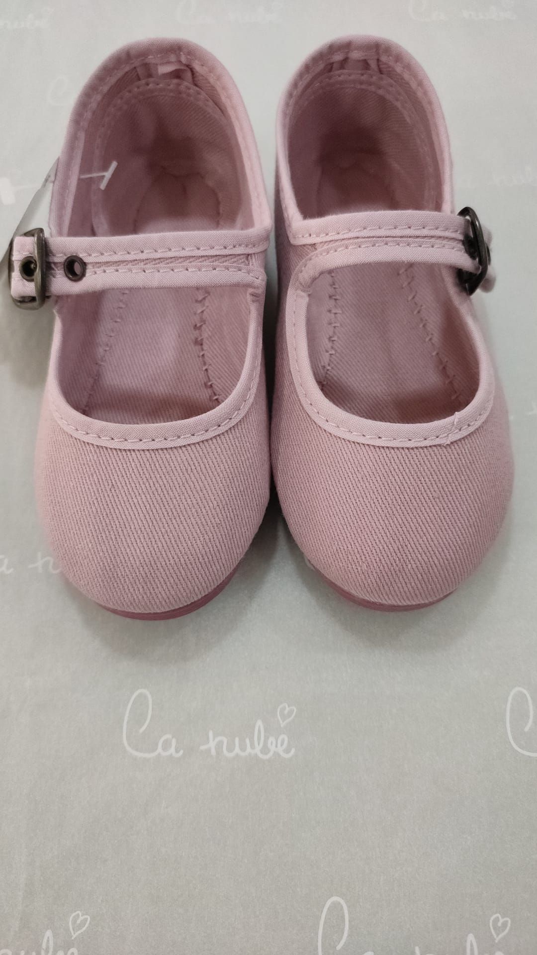 Un par de zapatos de bebé de color rosa están sobre una mesa.
