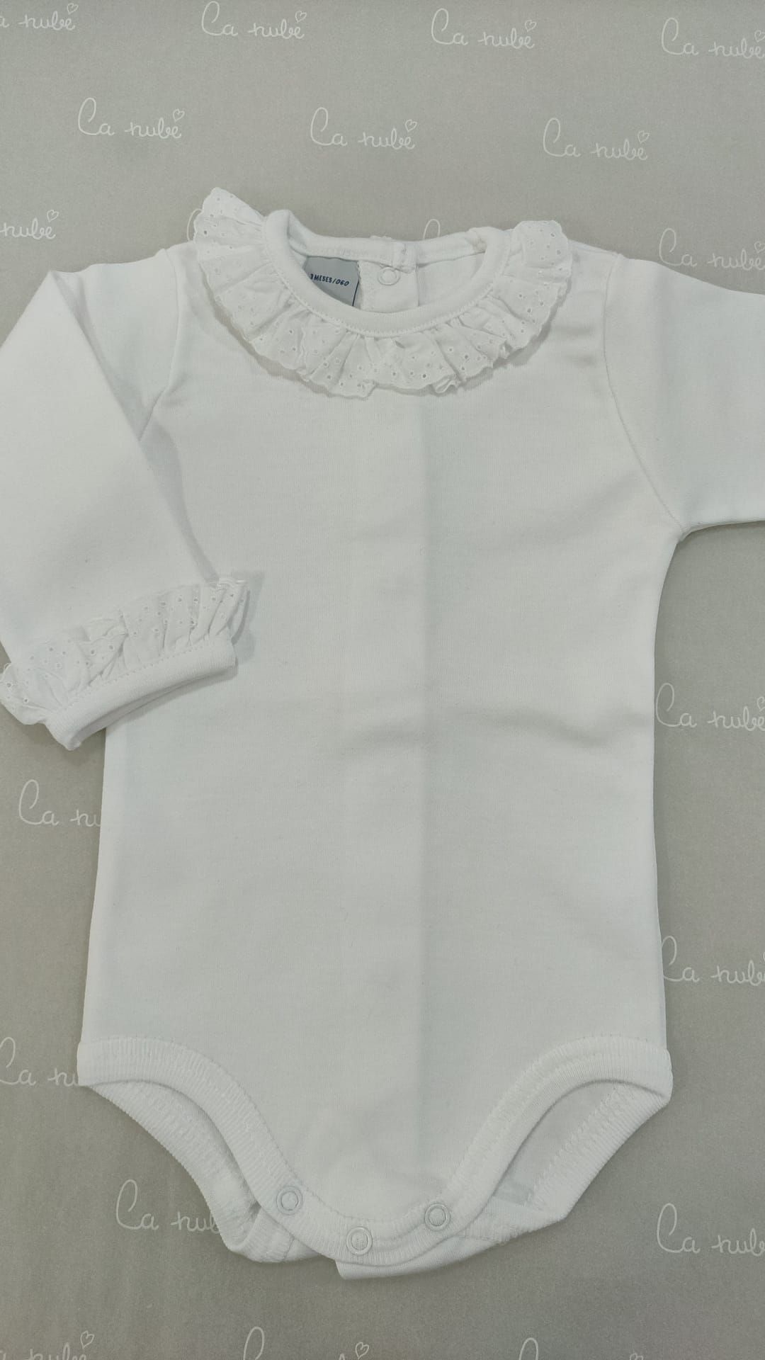 Un body de bebé blanco está sobre una mesa.