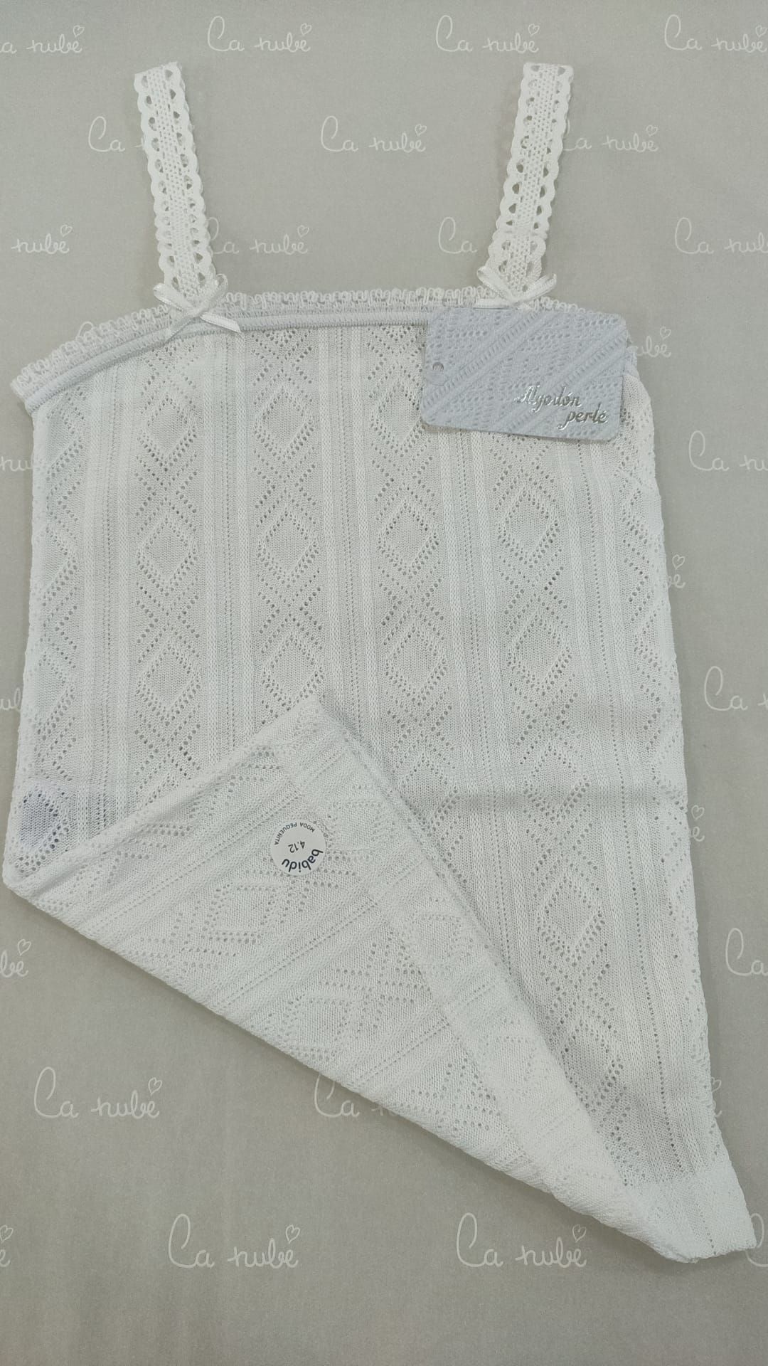 Un vestido de encaje blanco está doblado por la mitad sobre una mesa.