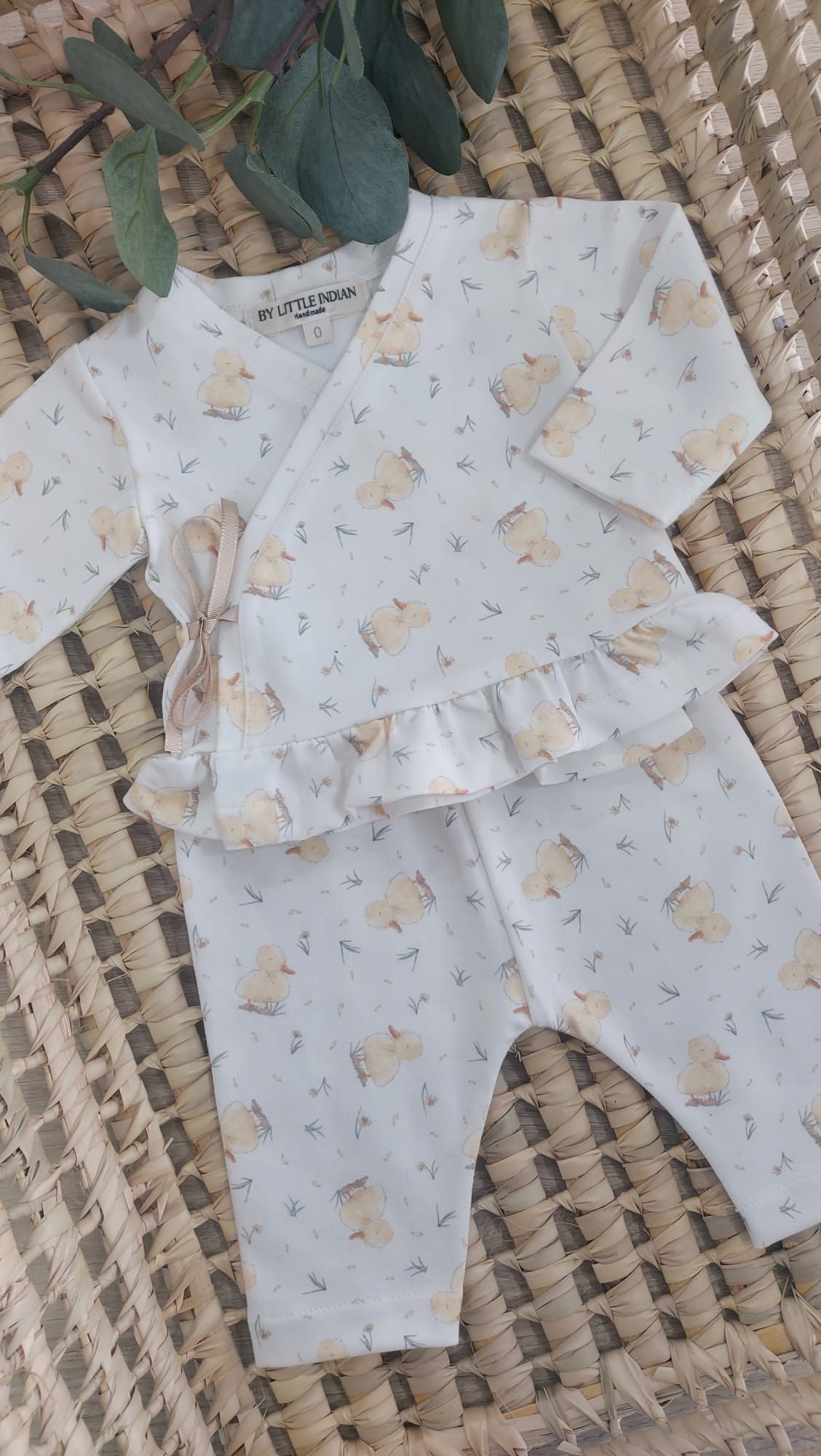 Un conjunto de bebé está sobre una manta de mimbre.