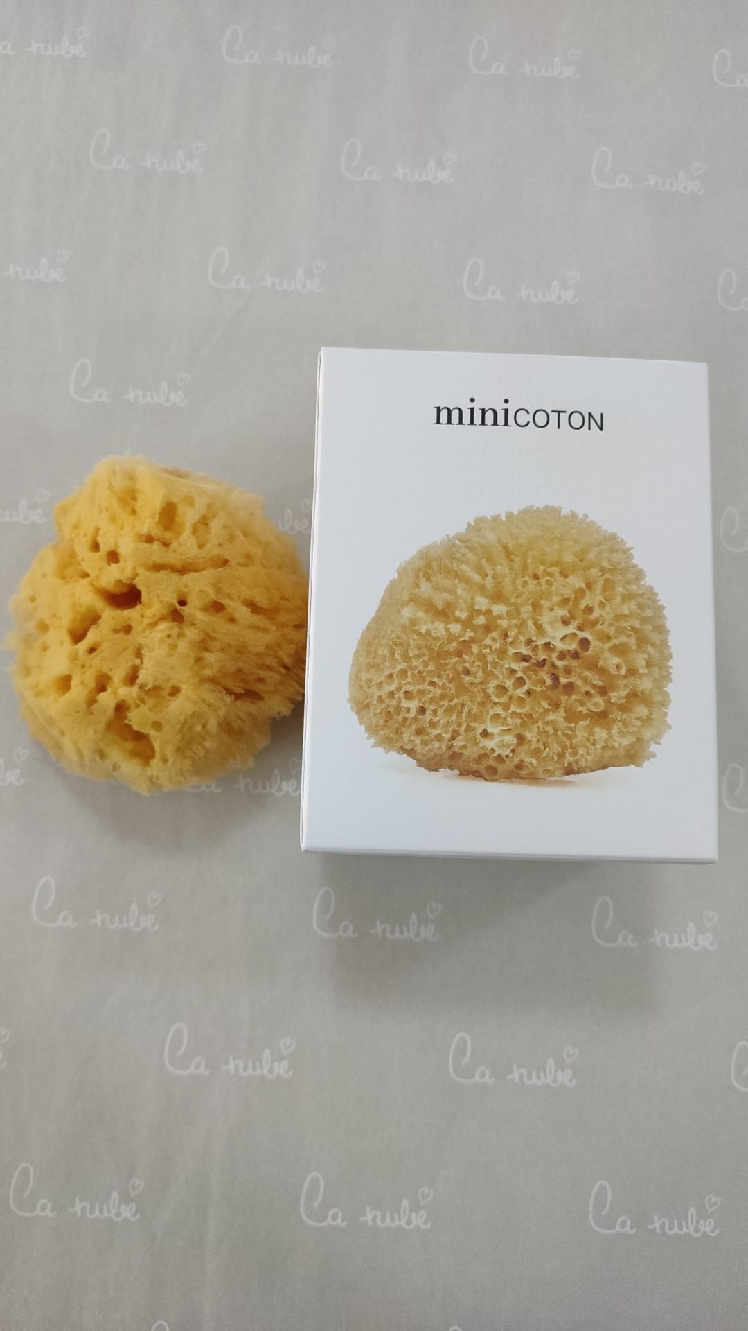 Una esponja está junto a una caja sobre una mesa.