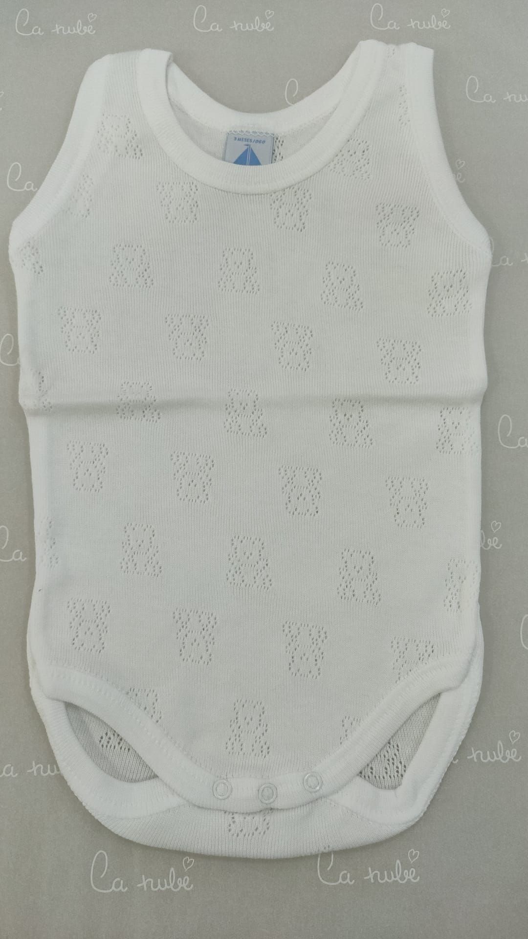 Un body de bebé blanco está sobre una mesa.