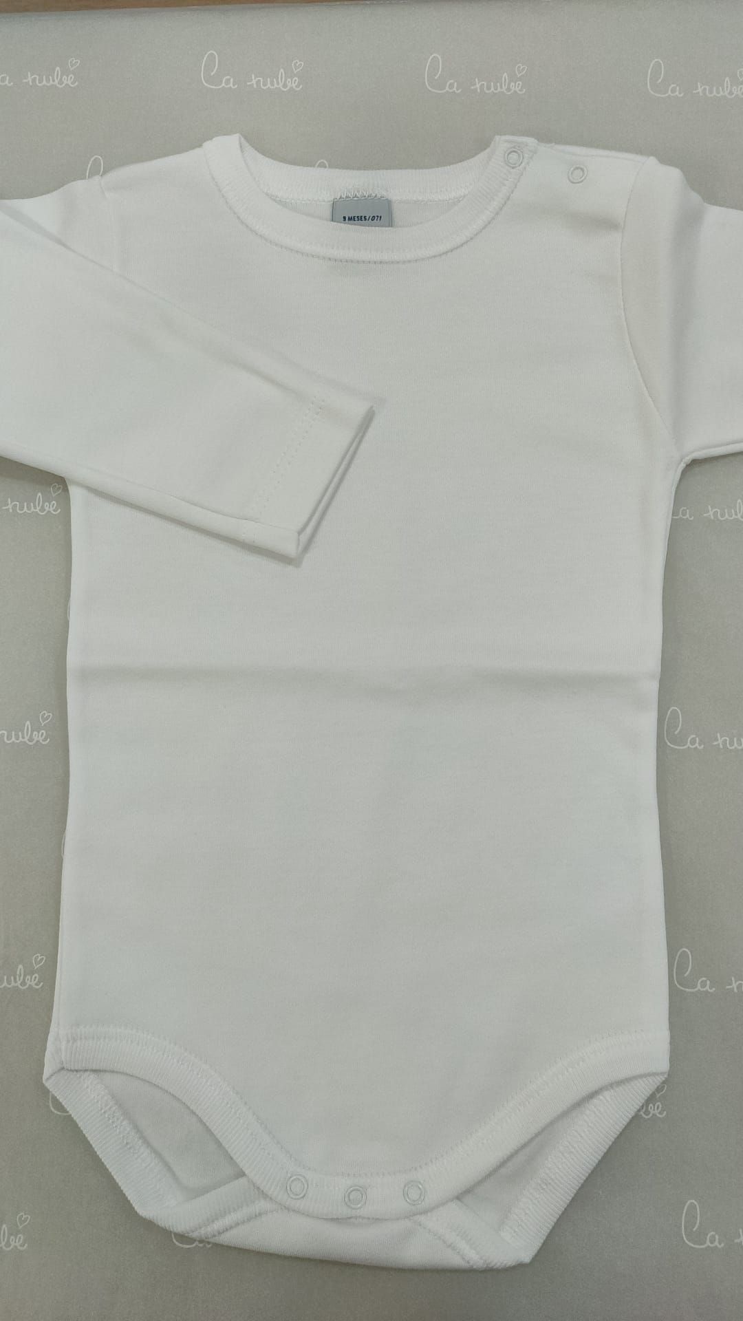 Un body de bebé blanco con mangas largas está sentado sobre una mesa.