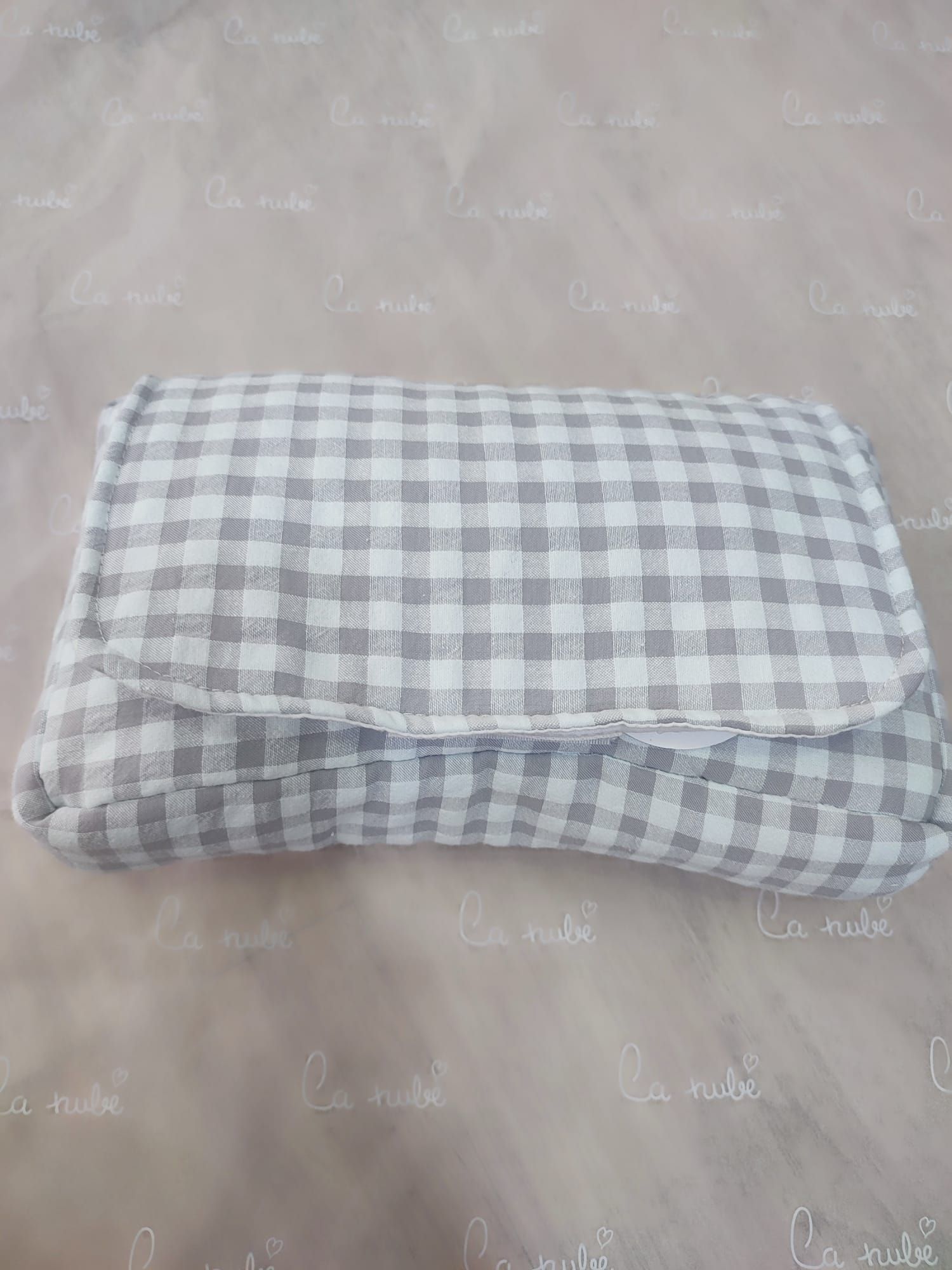 Un bolso a cuadros grises y blancos está sobre una mesa de madera.