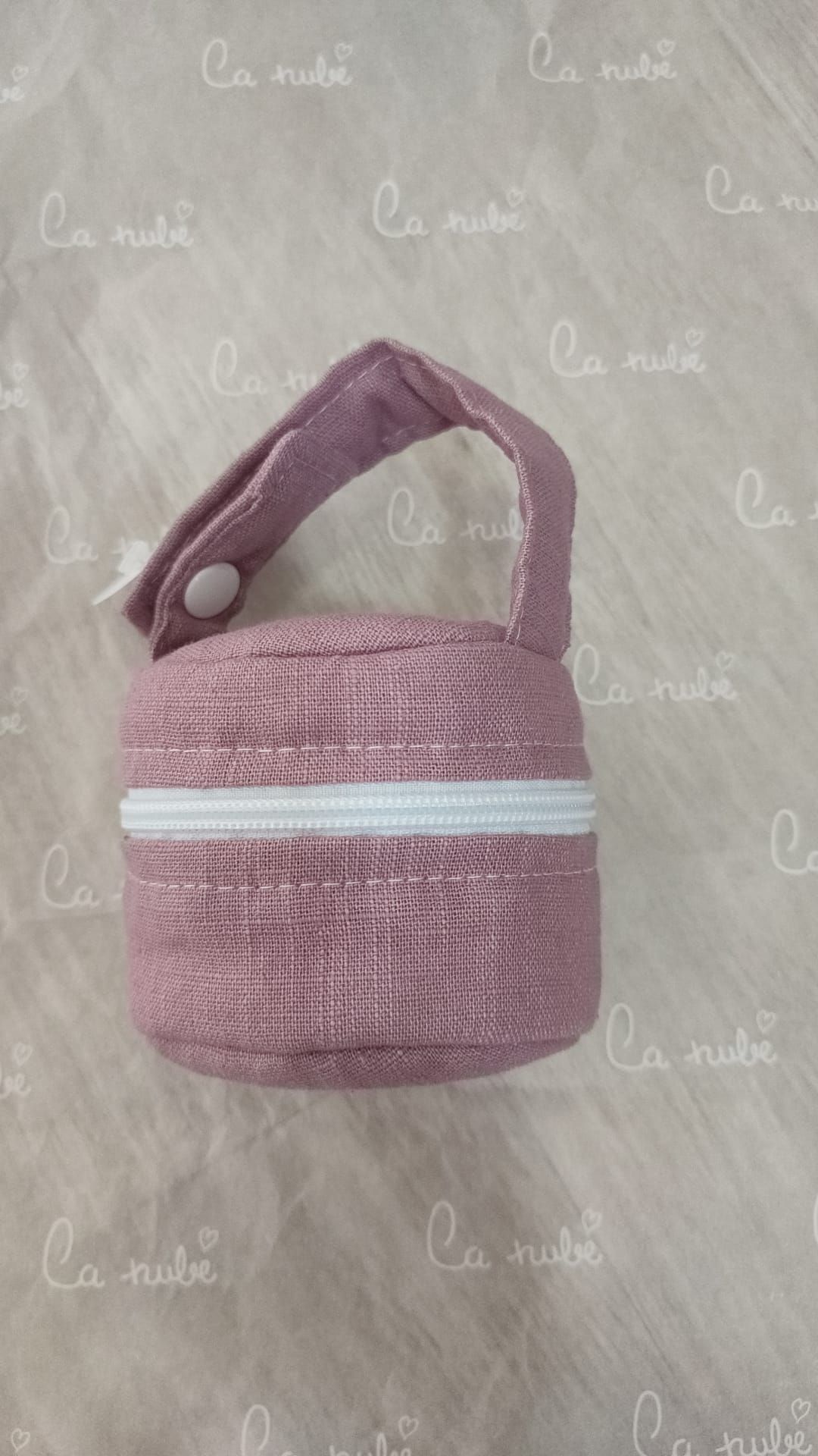 Una toalla rosa con una correa blanca alrededor está sobre una mesa.