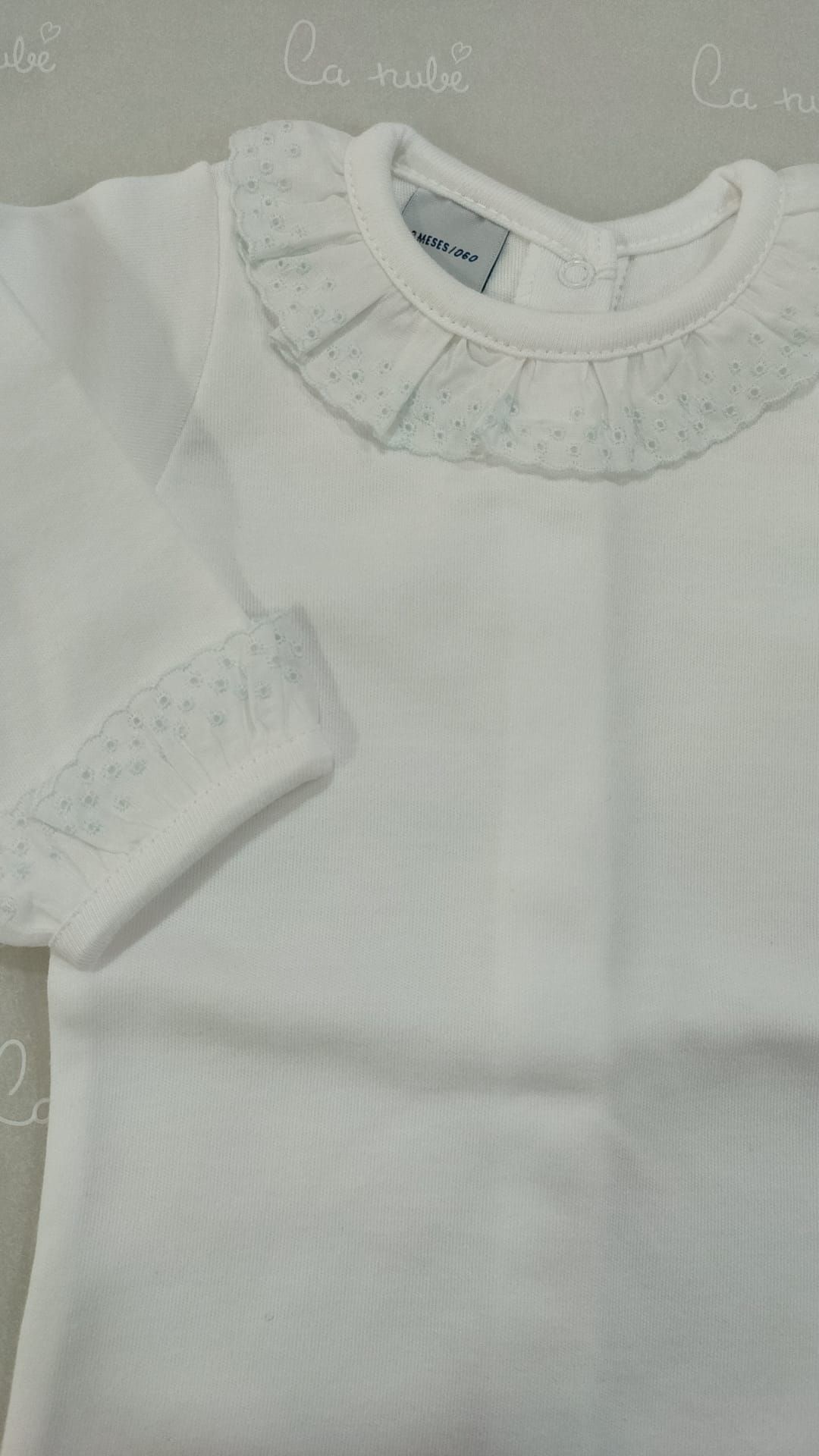 Una camisa blanca con cuello con volantes está sobre una mesa.