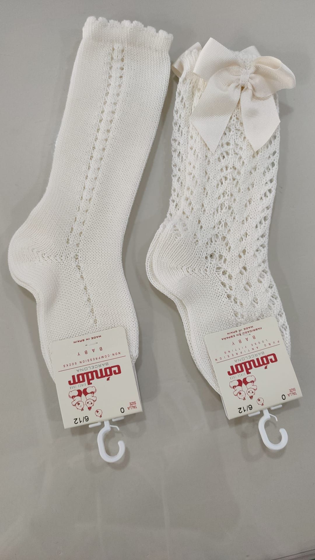 Dos calcetines blancos con lazos están sobre una mesa.