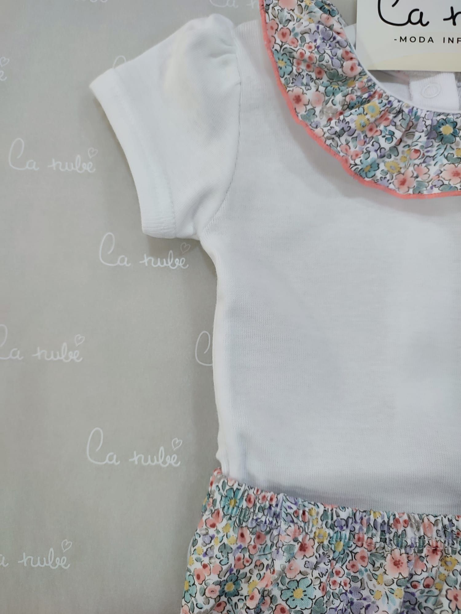 Una niña lleva una camisa blanca y pantalones cortos floreados.