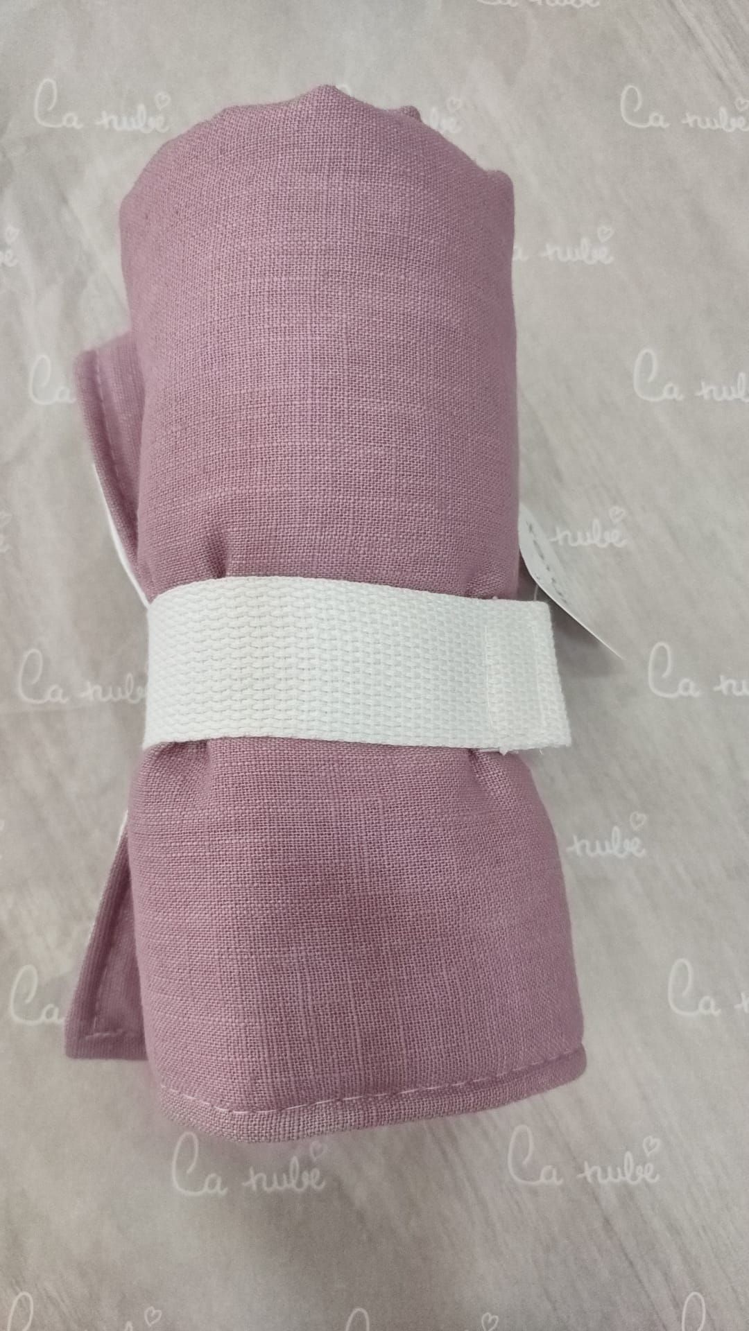 Una toalla rosa con una correa blanca alrededor está sobre una mesa.