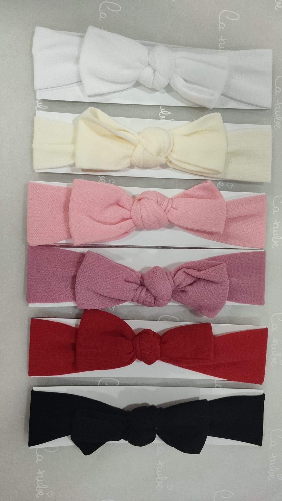 Un montón de diademas con lazos están alineadas sobre una mesa.