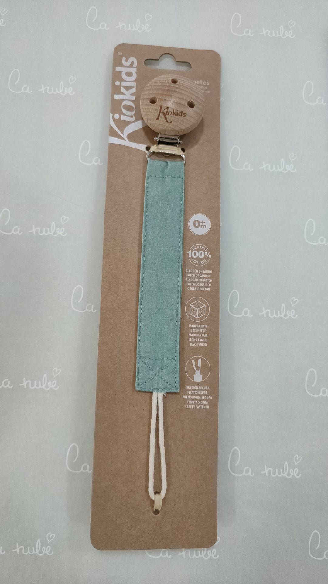 Un clip para chupete está sobre una mesa dentro de un paquete de cartón.