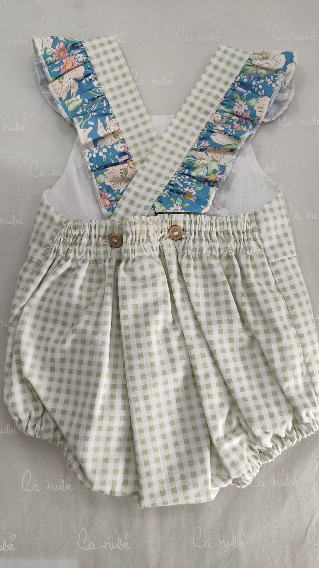 Una niña lleva un mono floral blanco y azul con tirantes.