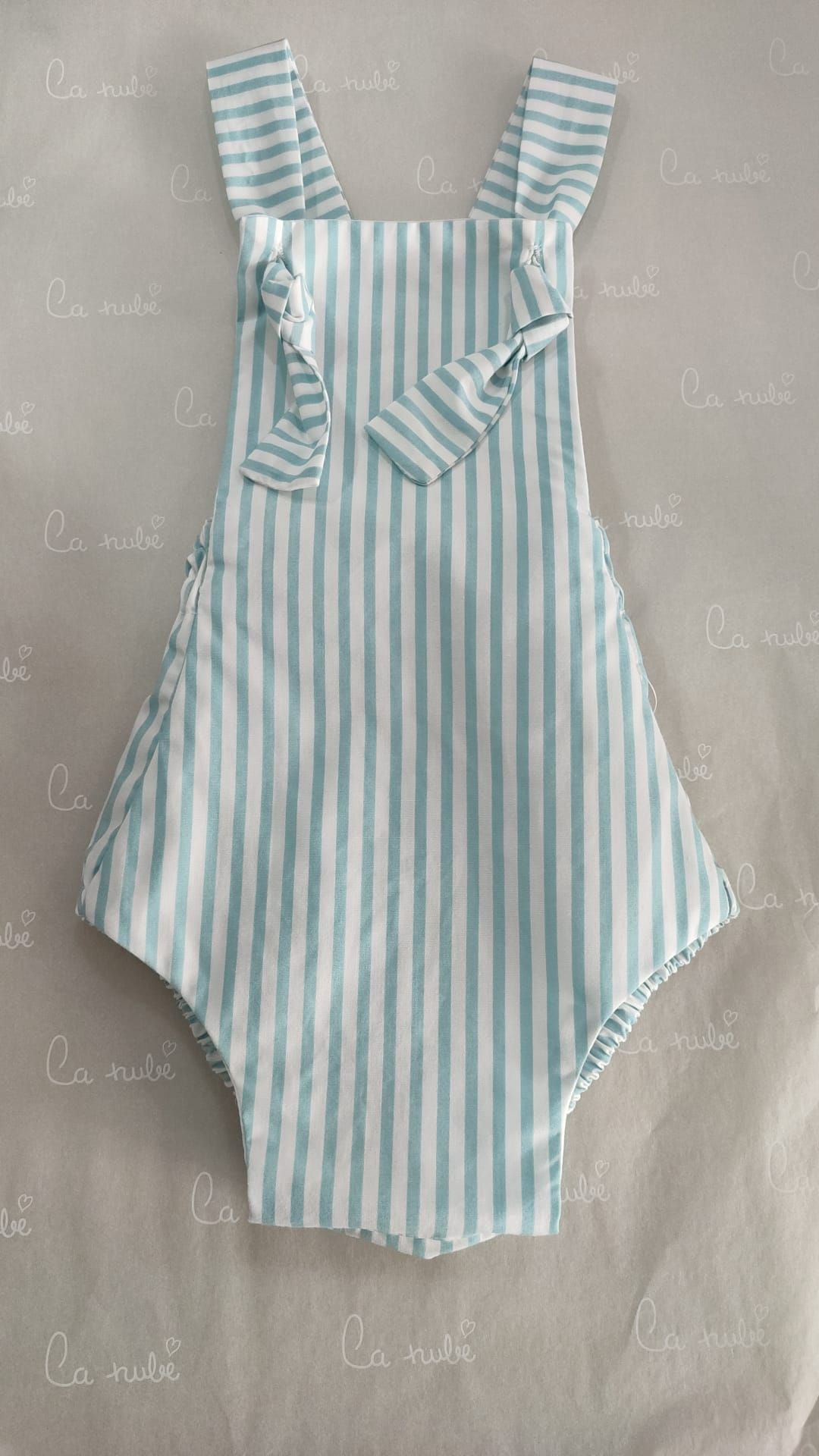 Un mono de rayas de bebé está sobre una cama.