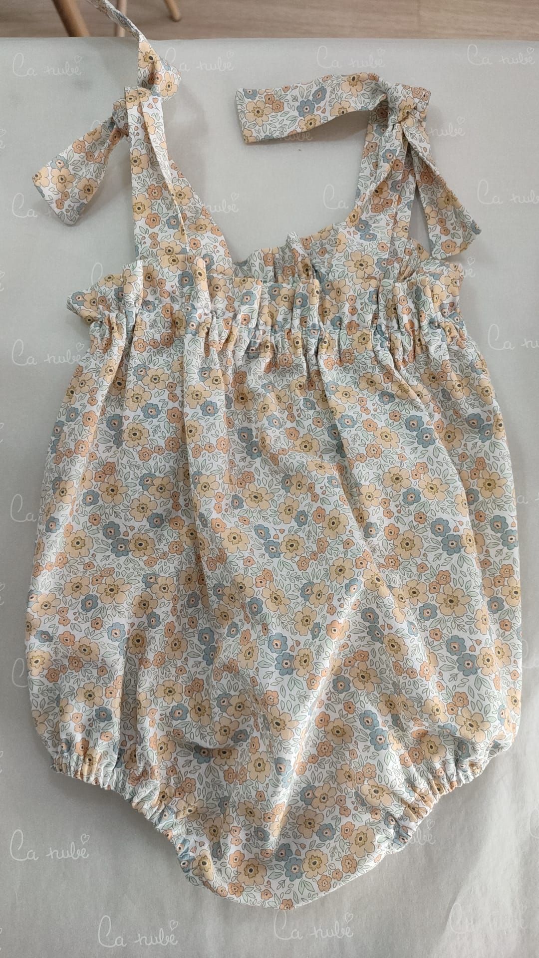 Un pelele floral de bebé está sobre una mesa.