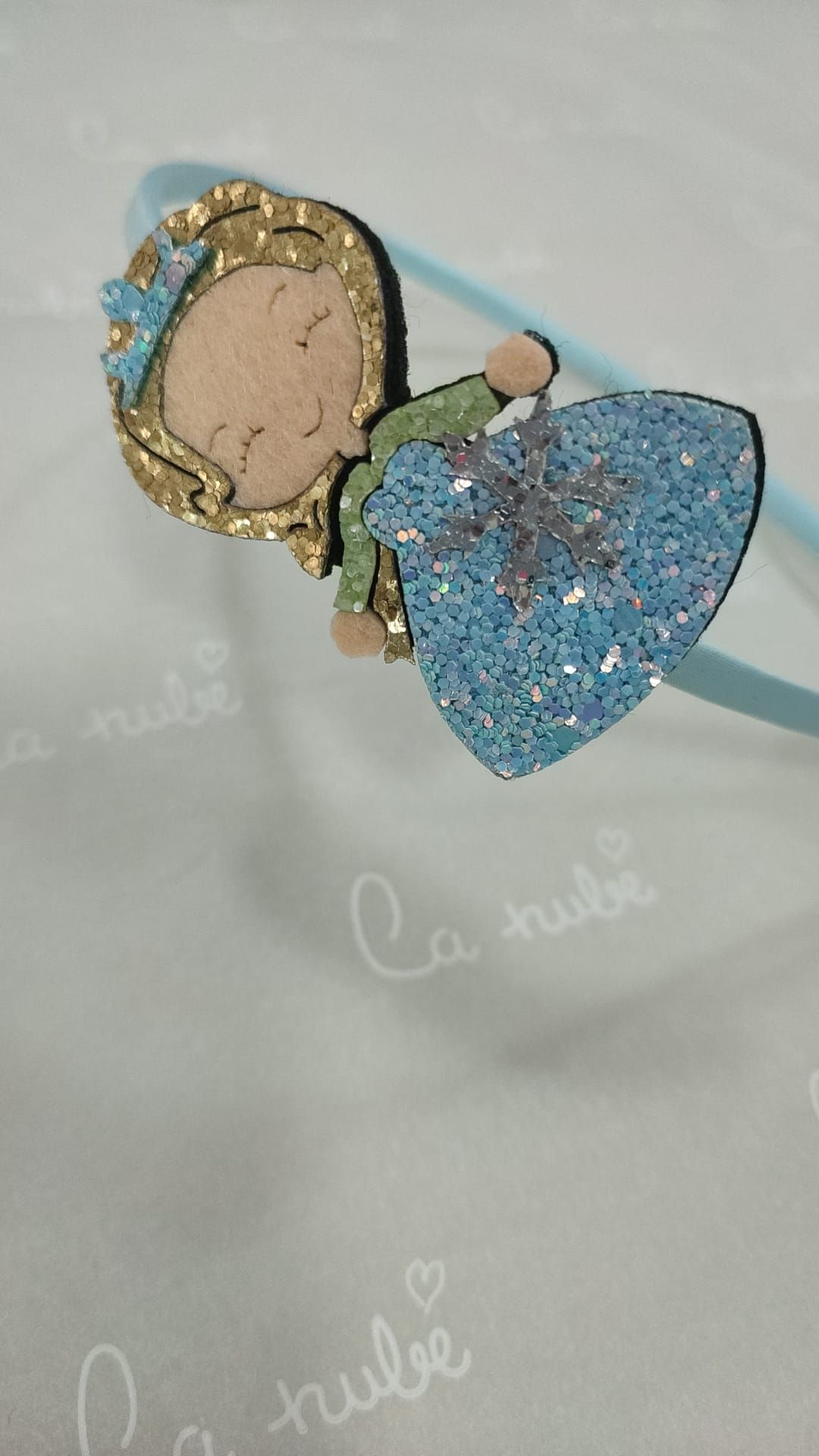 Una diadema con una niña con un vestido azul.