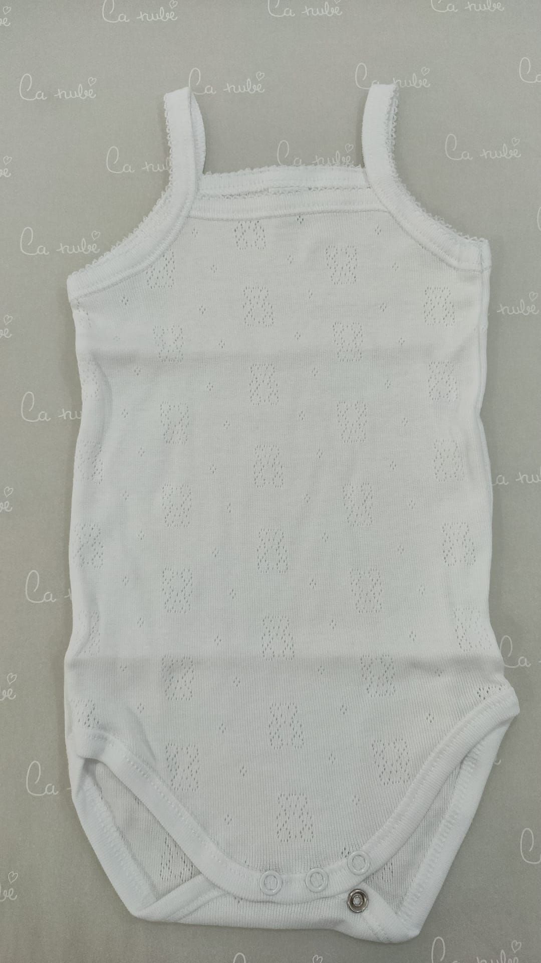 Un body de bebé blanco está sobre una mesa.