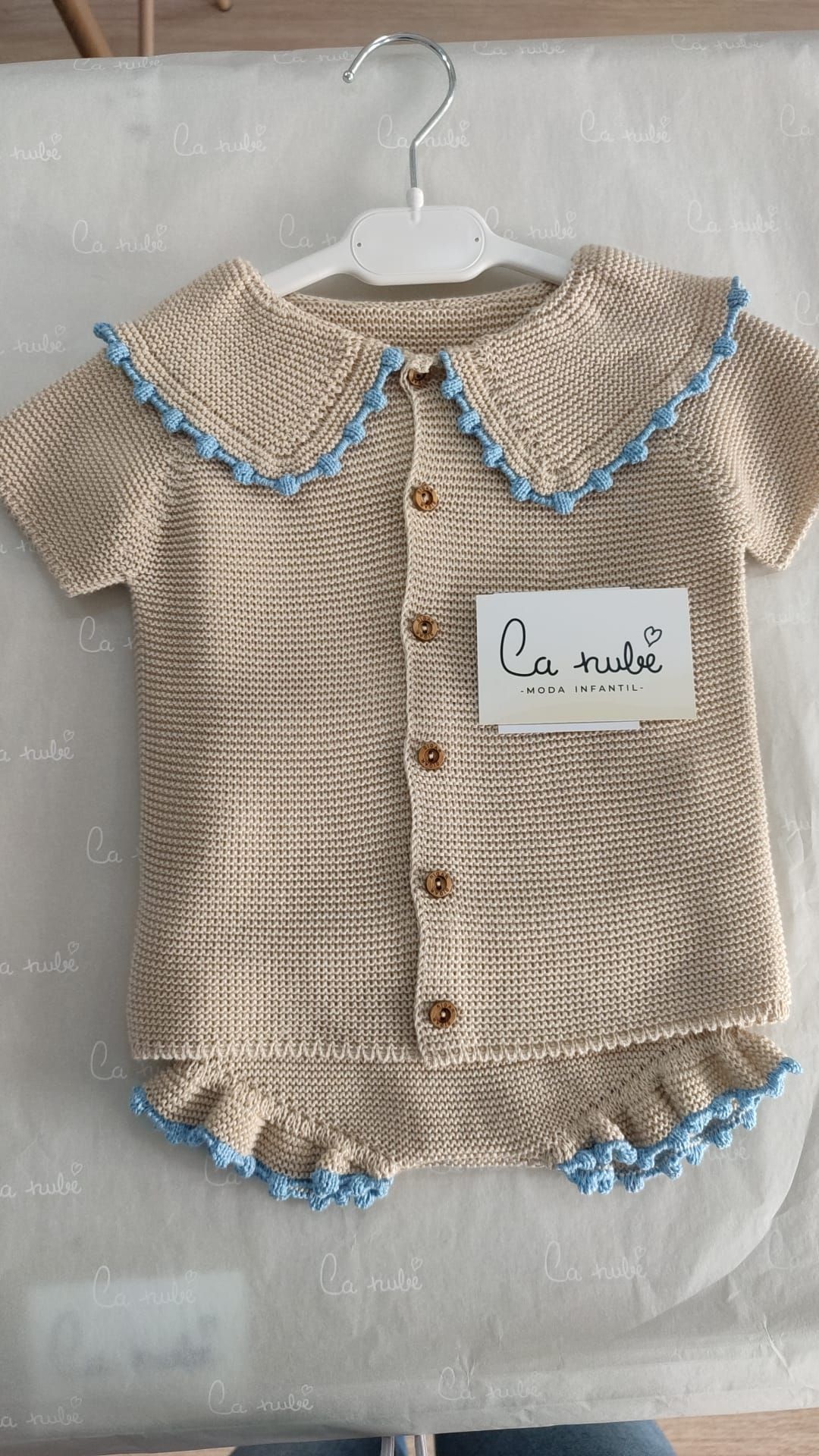 Un suéter de bebé está colgado en una percha sobre una mesa.