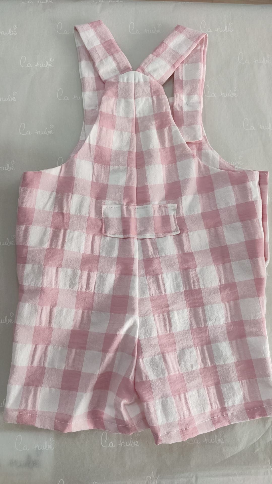 Se muestra la parte trasera de un mono a cuadros rosa y blanco.