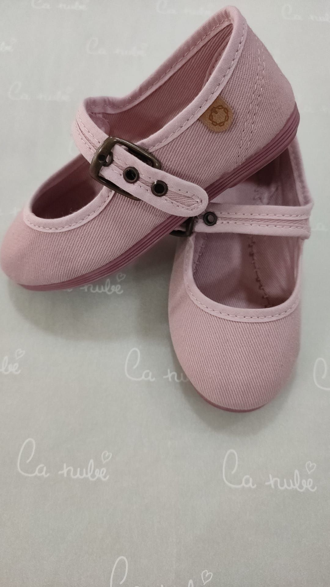 Un par de zapatos rosas con hebilla sobre una mesa.