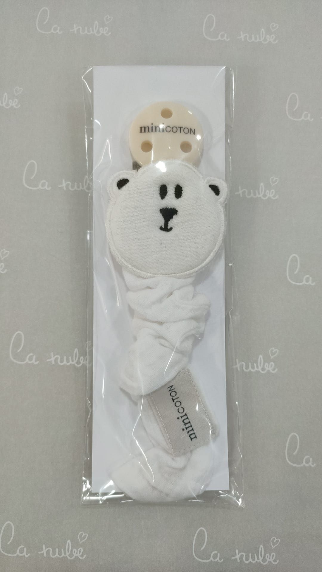 Un clip para chupete con la cara de un osito de peluche está dentro de una bolsa de plástico.