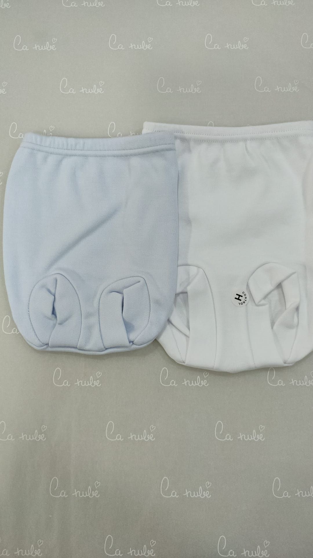 Dos pañales de bebé, uno azul y otro blanco, están sobre una mesa.